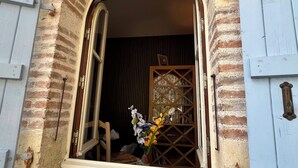 Una entrada con enrejado de madera, un pequeño escalón que la precede y una ventana con marco de madera.
