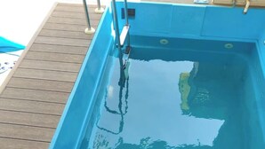 A rectangular swimming pool with a wooden deck surrounding it. - Steam and pool  with entire Roof top best to relax (Gurugram)