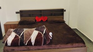 A bedroom with a wooden bed, a headboard, and a ceiling light fixture. - Steam and pool  with entire Roof top best to relax (Gurugram)