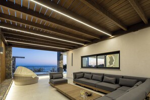 Ein modernes Wohnzimmer mit Sofa, Sitzsack und Couchtisch, mit Blick auf das Meer.