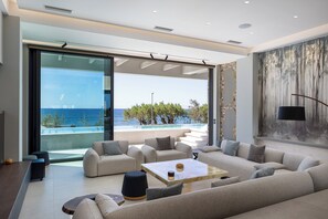Ein modernes Wohnzimmer mit einem großen Sofa, einem Couchtisch und Blick auf den Ozean.