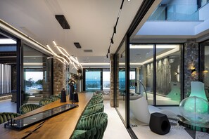 Un intérieur moderne avec un long comptoir d’accueil en bois, des fauteuils verts confortables et de grandes fenêtres en verre offrant une vue sur l’extérieur.