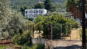 Un bâtiment blanc doté de nombreux balcons, entouré de verdure et avec des montagnes en arrière-plan.