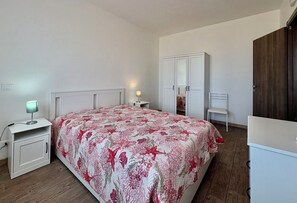 Una camera da letto con un letto, un comodino, una scrivania, una sedia, un armadio e uno specchio.