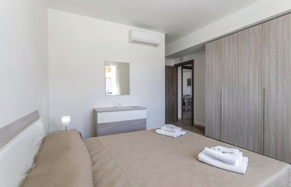A hotel room with a bed, a bedside table with a lamp, a mirror, a bathroom with a sink, and a wardrobe. - Villa in Marina Di Ragusa with 5 bedrooms sleeps 13 (Marina Di Ragusa)