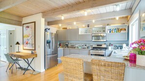 Una cocina con pisos de madera, electrodomésticos de acero inoxidable y sillas de mimbre.