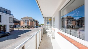 Un balcone con vista sulla strada, un edificio con facciata piastrellata e una finestra che riflette un altro edificio.