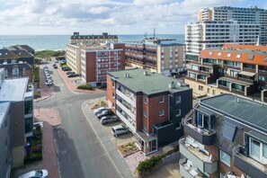 Ein Küstenabschnitt mit mehrstöckigen Gebäuden, einem Parkplatz und Blick auf das Meer.