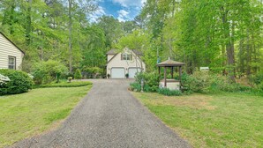 A gravel driveway leading to a house with a garage, surrounded by lush greenery and trees. - Pool Access! Cozy Couple's Getaway in Kilmarnock (Kilmarnock)