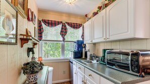 A kitchen with white cabinets, a microwave, and a window with plaid curtains. - Pool Access! Cozy Couple's Getaway in Kilmarnock (Kilmarnock)