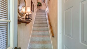 A carpeted staircase with a handrail, a wall-mounted mirror, and a small table with a lamp. - Pool Access! Cozy Couple's Getaway in Kilmarnock (Kilmarnock)