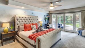 Een slaapkamer met een groot bed, een plafondventilator en uitzicht door een schuifdeur.