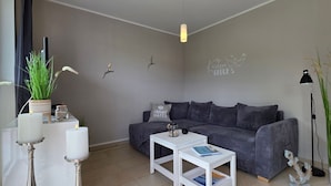 Una sala de estar moderna con un sofá gris, una mesa de centro blanca y una lámpara de pie.
