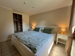 Ein Schlafzimmer mit einem Bett, zwei Nachttischen, einem Schrank und einer Heizung.