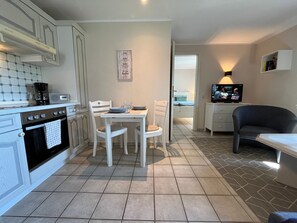 A compact kitchen with a dining table, chairs, a coffee maker, and a TV. - Separate bungalow, 30sqm for up to 2 people - Nordgang 6 (Sylt-Ost)