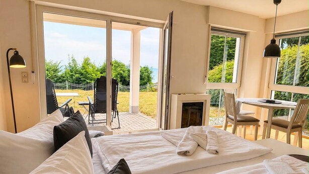 Ein Hotelzimmer mit Bett, Tisch, Stühlen und Blick ins Freie.