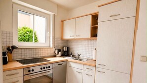 Eine moderne Küche mit Fenster, Edelstahlgeräten und hellen Schränken.