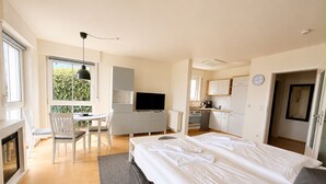 Ein modernes Schlafzimmer mit einem großen Bett, einem Schreibtisch und einer Küchenzeile.