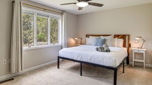 Une chambre à coucher avec un lit, des lampes de chevet, un ventilateur de plafond et une fenêtre avec des rideaux.