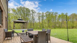 Une terrasse en bois avec des meubles en osier et un kiosque.