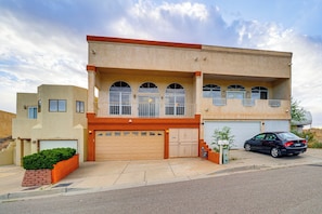 Ein zweistöckiges Haus mit Garage, ein Auto davor und ein klarer Himmel.