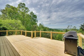 Eine Holzterrasse mit Geländer, mit Blick auf eine bewaldete Landschaft.