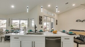 A modern kitchen with a large island, white cabinetry, and pendant lighting. - Waterfront Pool Home by Park Pickleball Sleeps 10 (Cape Coral)