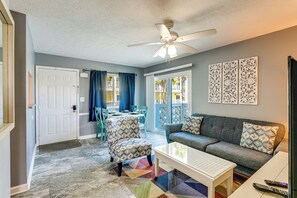Ein Wohnzimmer mit Deckenventilator, einer Couch, einem Couchtisch und einem gemusterten Sessel.