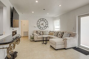 Ein Wohnzimmer mit Ecksofa, runder Wanduhr, Flachbildfernseher und Kamin.