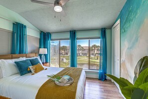 Ein Hotelzimmer mit Bett, Deckenventilator, Fenster mit Blick auf einen Golfplatz und einer großen Pflanze.