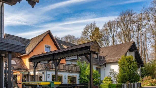 A building with a covered outdoor seating area, a small garden, and a paved driveway. - 4 Person Holiday Park Home in Horhausen (Obersteinebach)