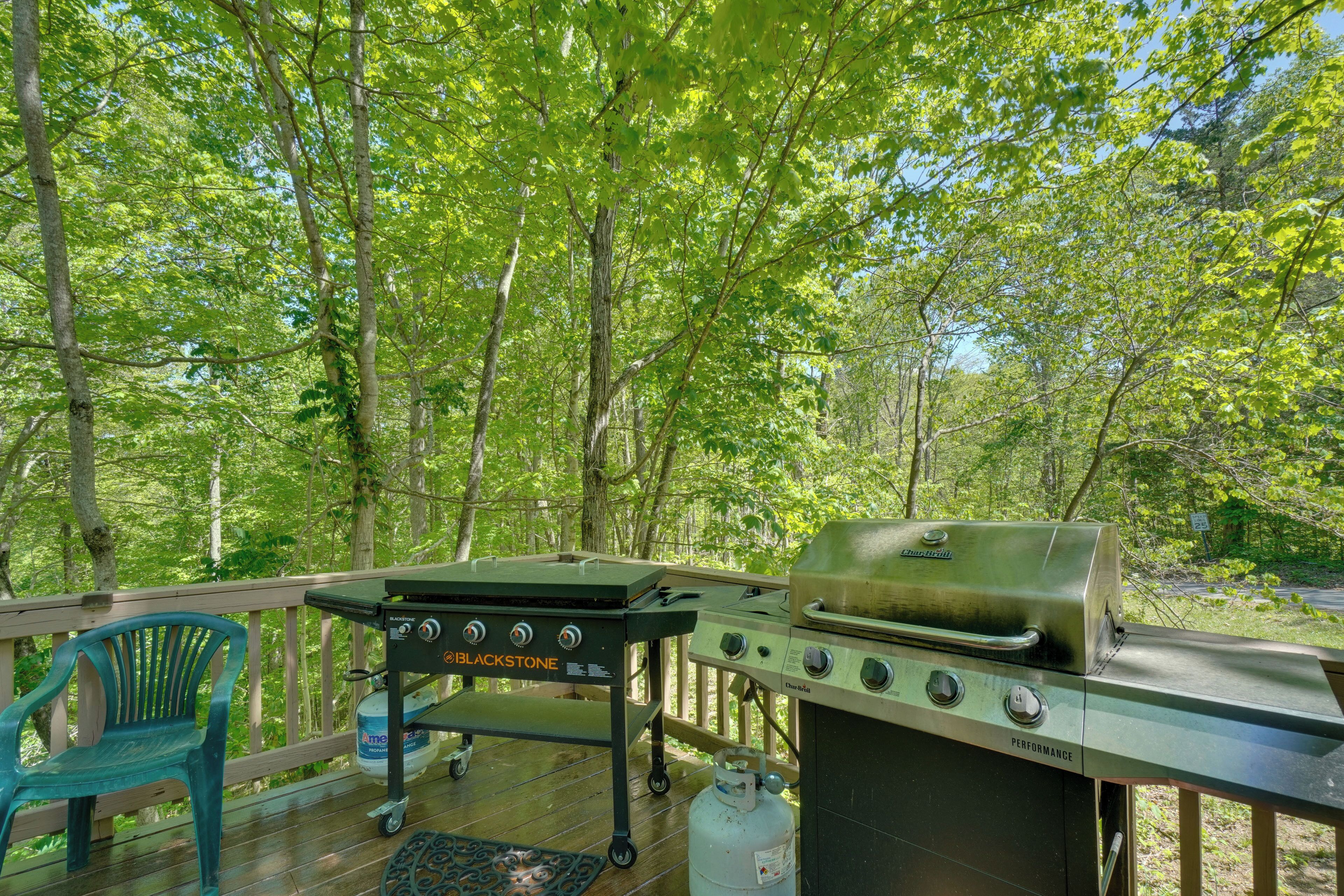 A deck with a grill, a chair, and a propane tank.