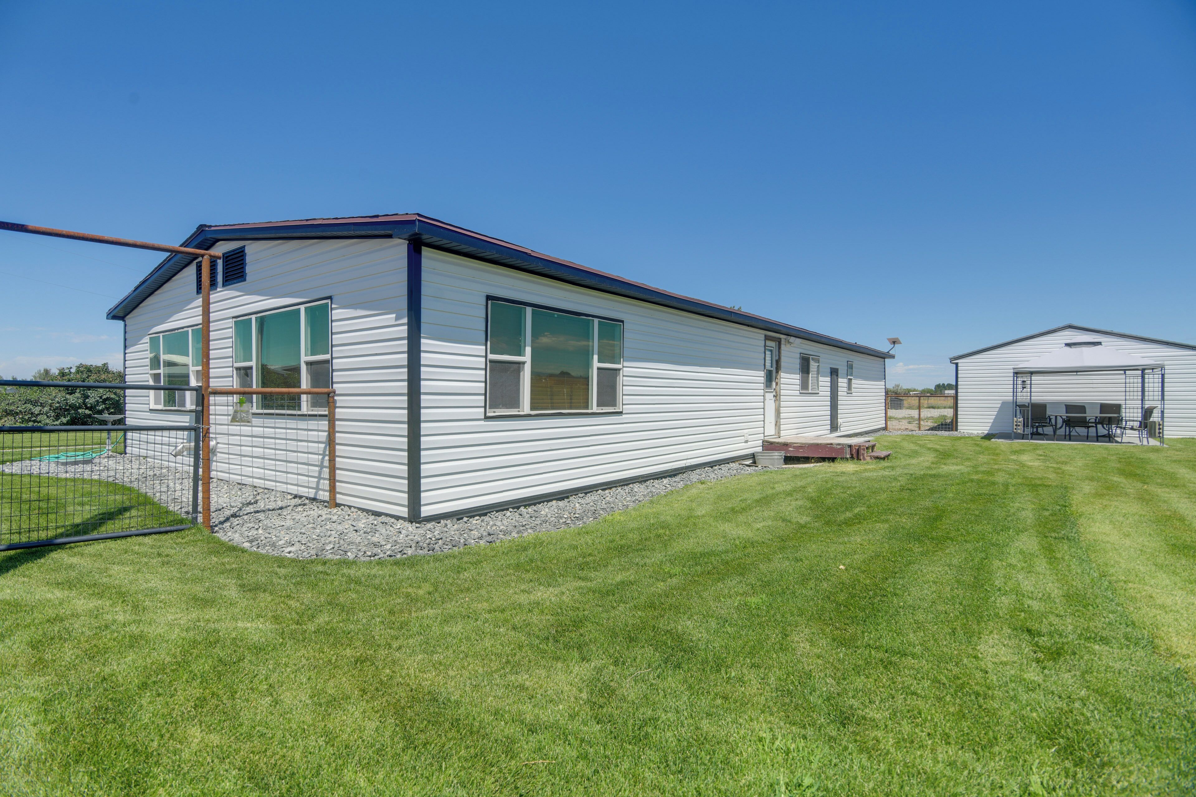 A single-story mobile home with a flat roof, large windows, and a small porch area.