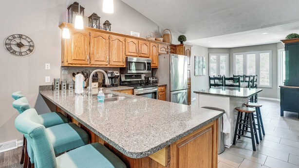 A kitchen with wooden cabinets, a granite countertop, bar stools, and a large island. - 2 Mi to Dale Hollow Lake! 'Shadowood' Group Escape (Byrdstown)