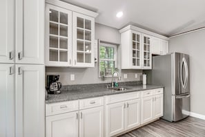 A modern kitchen with white cabinetry, a stainless steel refrigerator, and a granite countertop. - 2 Mi to Dale Hollow Lake! 'Shadowood' Group Escape (Byrdstown)