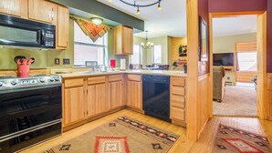 A kitchen with wooden cabinets, a microwave, an oven, and a dishwasher. - Walk to Angel Fire Resort! Mtn-View Condo Near Fun (Angel Fire)