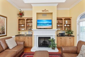 A living room with a fireplace, a television, and a 'relax' sign above it. - Luxury Beach Condo, Pool, 2 Min Walk to Beach (Myrtle Beach)
