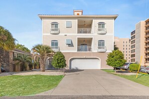 A multi-story residential building with a garage, balconies, and a clear sky. - Luxury Beach Condo, Pool, 2 Min Walk to Beach (Myrtle Beach)