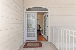 A hallway with a white door, a white railing, and a rug on the floor. - Luxury Beach Condo, Pool, 2 Min Walk to Beach (Myrtle Beach)