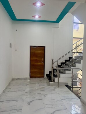 A hallway with a wooden door, a staircase with metal railings, and a tiled floor. - Welcome to the beautiful and friendly place
300meters away From all famous place (Ayodhya)