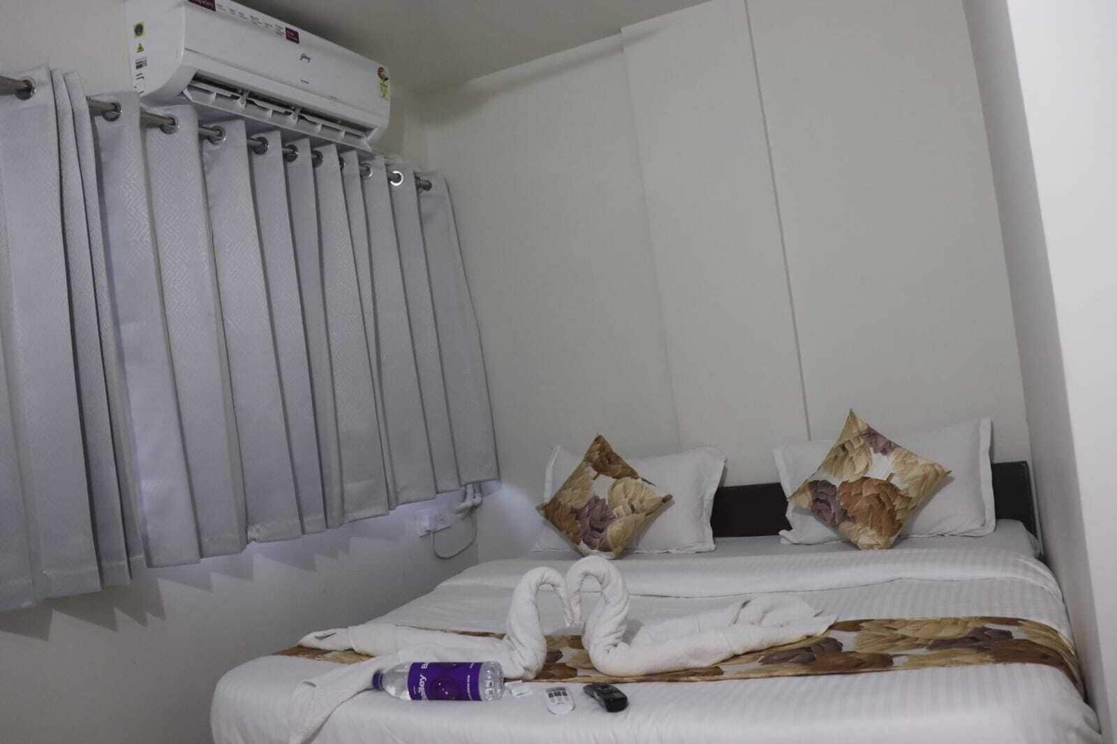 Una habitación de hotel con una cama, un radiador, un control remoto y una botella sobre la cama.