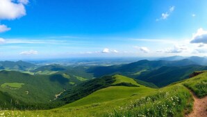 Een panoramisch uitzicht op een bergachtig landschap met groene valleien en een helderblauwe lucht.