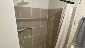 Ett litet, avskilt duschutrymme med ett duschmunstycke, en handdukshängare och en duschdraperi.
