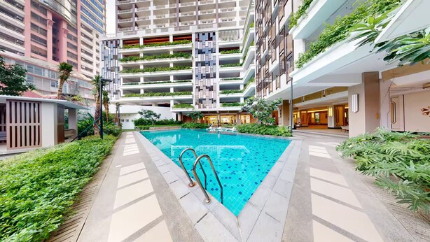 En modern bostadsbyggnad med en central pool, balkonger med planteringar och en stilren, samtida design.