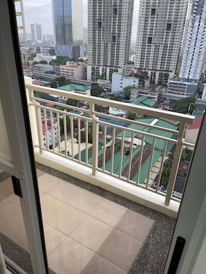 Ein Balkon mit Blick auf eine Stadtlandschaft, darunter Hochhäuser und ein Gebäude mit Gründach.