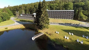A hotel with a large building, a dock, and a grassy area with lounge chairs. - 2 Person Holiday Park Home in Erlbach (Markneukirchen)