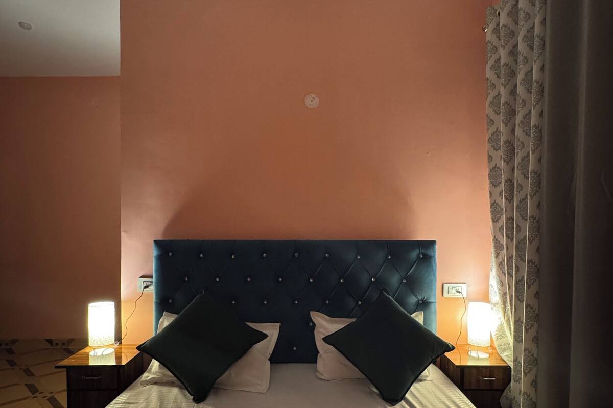 Une chambre d’hôtel avec un grand lit, deux lampes de chevet, une tête de lit et une table de chevet.
