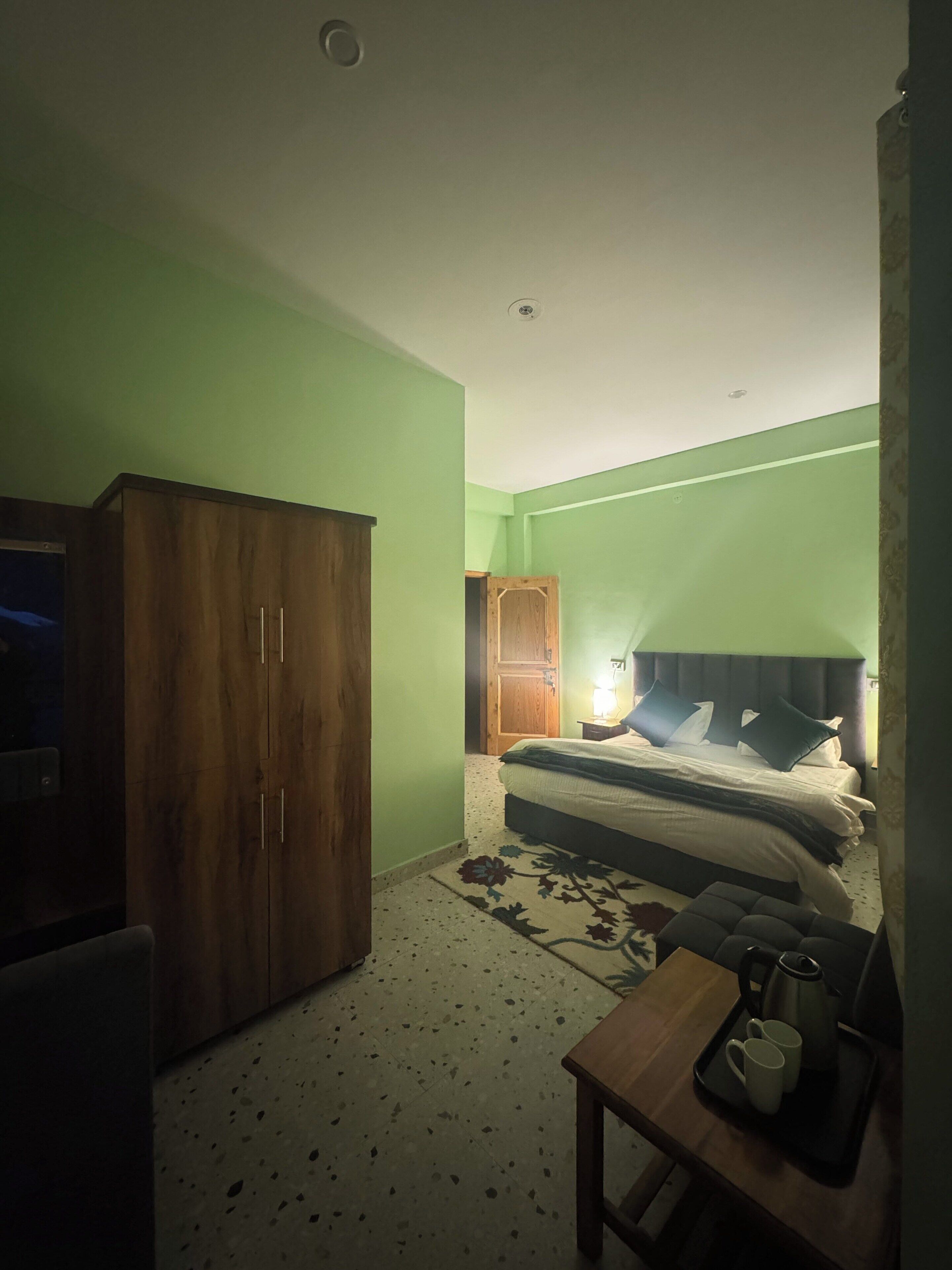 Un dormitorio con cama, un armario de madera, una mesita con bandeja y una mesilla de noche.