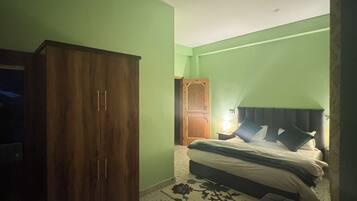 Un dormitorio con cama, un armario de madera, una mesita con bandeja y una mesilla de noche.