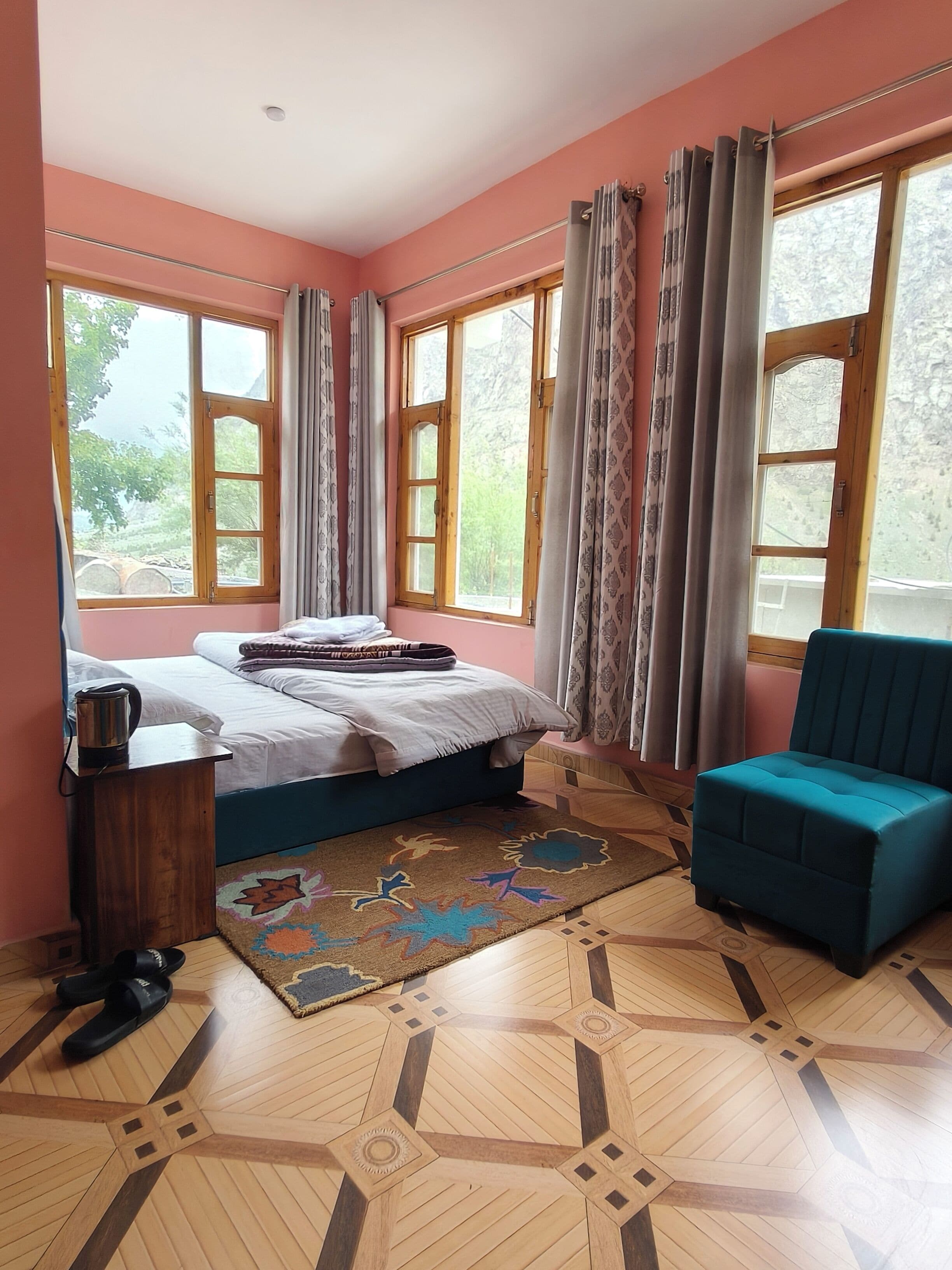 A bedroom with a bed, a chair, a small table, and a window with curtains.